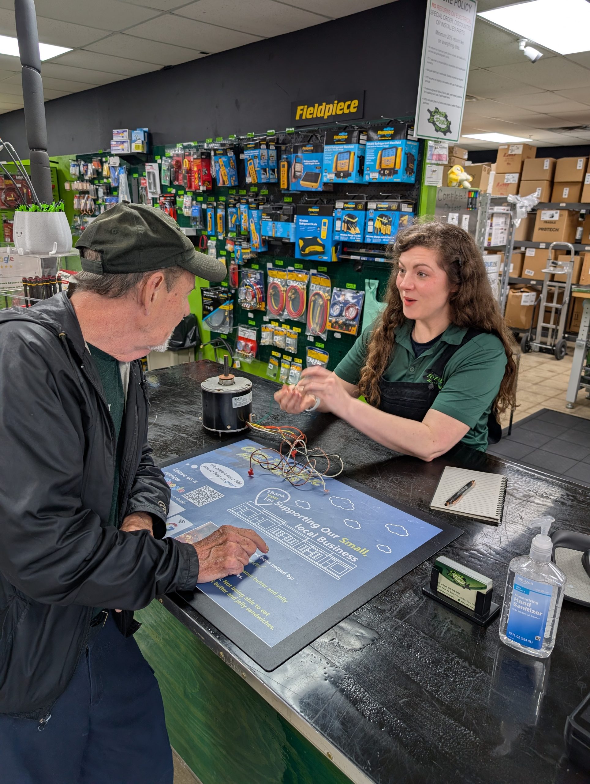 Staff member explaining condenser motor wiring to customer at the counter at Open To Public HVAC Parts in Dallas TX